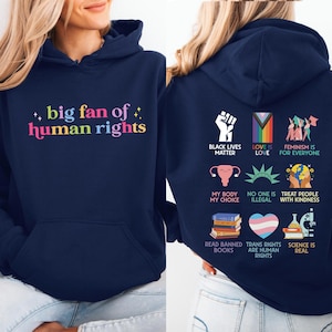 May include: Navy blue hoodie with the text "big fan of human rights" in colorful letters on the front. The back features various social justice symbols and phrases, including "Black Lives Matter" and "Love is Love."