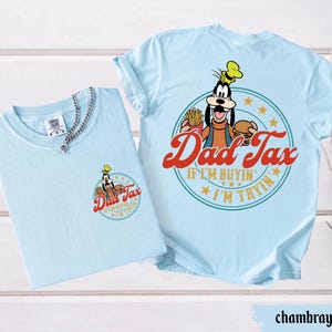 May include: Two light blue t-shirts. One shirt has a small graphic of Goofy with the words "Dad Tax" and "If I'm buyin' I'm tryin'". The other shirt has a larger version of the same graphic on the back.