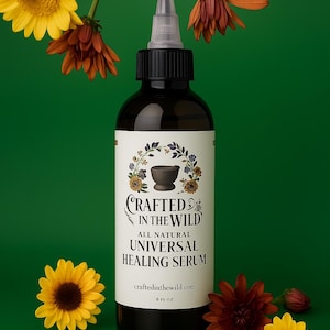 May include: A dark brown bottle of "Crafted in the Wild" Universal Healing Serum with a white label and a black cap. The label features a mortar and pestle illustration. The background is green with yellow and orange flowers.