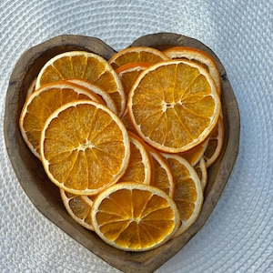 Peut inclure: Un bol en bois en forme de c&oelig;ur rempli de tranches d'orange s&eacute;ch&eacute;es. Les tranches d'orange sont dispos&eacute;es en cercle et sont d'une couleur orange vibrante.