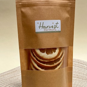 Peut inclure: Un sac en papier brun avec une fen&ecirc;tre transparente montrant des tranches d'orange s&eacute;ch&eacute;es &agrave; l'int&eacute;rieur. Le sac porte une &eacute;tiquette qui dit "Harvest Harmony".