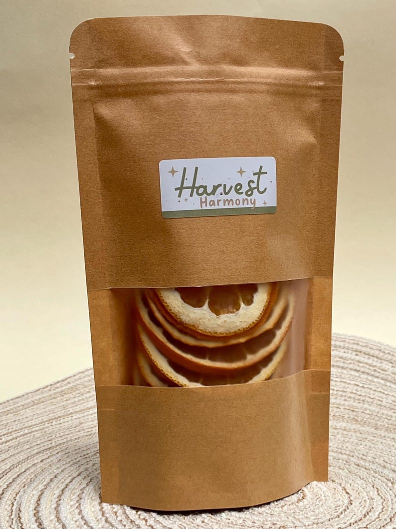 Peut inclure: Un sac en papier brun avec une fen&ecirc;tre transparente montrant des tranches d'orange s&eacute;ch&eacute;es &agrave; l'int&eacute;rieur. Le sac porte une &eacute;tiquette qui dit "Harvest Harmony".