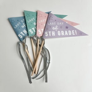 May include: A collection of colorful pennant flags for the last day of 5th grade. Each flag is a different pastel color, with the text "LAST DAY of 5TH GRADE!" and star graphics. Silver ribbons and wooden sticks are attached.