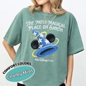 May include: Chalky mint green t-shirt with the text "The Most Magical Place on Earth" and a blue wizard hat graphic with white stars. The shirt also has the words "Walt Disney World" printed below the graphic.