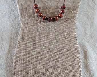 Handgemaakte ketting met bruine pauwenparel en donkerbruin leer.
