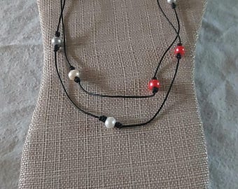 Collar hecho a mano de perlas rojas, plateadas y blancas y cuero negro.