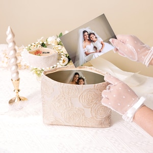 K&ouml;nnte beinhalten: Eine wei&szlig;e Erinnerungsbox mit Blumenmuster und einem Foto einer Braut und ihrer Blumenm&auml;dchen im Inneren. Die Box tr&auml;gt die Aufschrift "MOM".