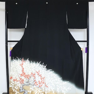 May include: A black kimono with a floral design. The kimono features a gradient from black to white and gold at the bottom, with a detailed illustration of a flowering tree. The garment is displayed on a black stand.