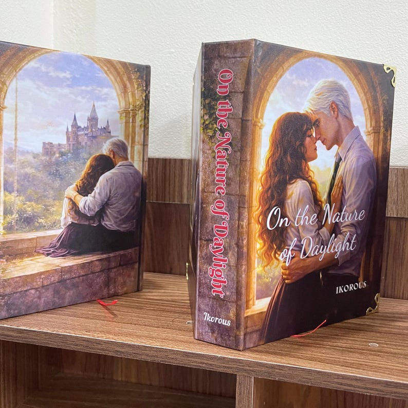 May include: Two hardcover books with the title "On the Nature of Daylight." One book features a couple embracing, the other shows a couple kissing. The spines display the title vertically. The author's name, "Ikorous," is visible on one book.