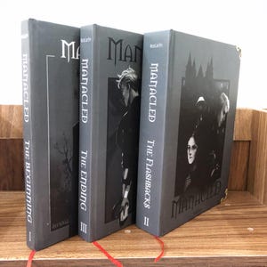 May include: A set of three hardcover books with gray covers. The titles are "The Beginning", "The Ending", and "The Flashbacks". Each book has the title "MANACLED" in large white letters. The spines have the series title and author's name.