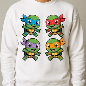 May include: White sweatshirt featuring a colorful graphic of four cartoon turtles, each with a different colored mask: blue, red, purple, and orange. The turtles have green skin and are smiling. The design is centered on the front of the sweatshirt.