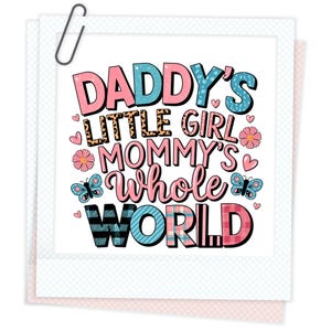 以下が含まれることがあります： 白地にピンク、ブルー、ブラックのグラフィックテキスト。テキストは「Daddy's Little Girl Mommy's Whole World」です。