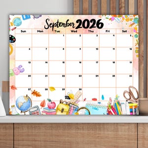 May include: A rectangular wall calendar for September 2026 featuring a grid layout with black text. The border is decorated with watercolor illustrations of school supplies including a globe, books, an apple, a backpack, and scissors.