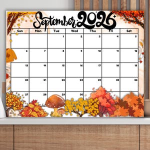 May include: A rectangular wall calendar for September 2026 featuring a grid layout with black text. The design includes illustrations of autumn leaves, trees, and mushrooms in shades of orange, yellow, and brown along the top and bottom borders.