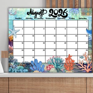 Könnte beinhalten: Ein dekorativer August 2026 Kalender mit Unterwasser-Thema. Der Kalender hat ein weißes Raster mit Daten und Wochentagen. Der Rand ist mit bunten Korallen, Seesternen und Meeresbewohnern verziert. Der Text "August 2026" ist in einer verspielten Schrift geschrieben.