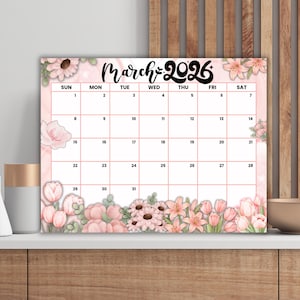Puede incluir: Un calendario floral para marzo de 2026, con un diseño rosa y blanco y varias flores. La cuadrícula del calendario es de color rosa claro, con los días de la semana en la parte superior. El texto "March 2026" está en una fuente decorativa.