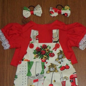 Peut inclure: Une chemise rouge à manches courtes avec une bordure en dentelle blanche, associée à une salopette crème à motif de cuisine avec des fleurs, des horloges et des appareils, accompagnée de deux nœuds pour cheveux assortis avec élastiques.