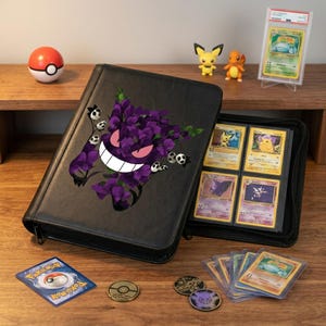 Puede incluir: Carpeta negra para cartas Pokémon con un diseño de Gengar morado y detalles florales. La carpeta está abierta, mostrando varias cartas Pokémon. También hay figuras, monedas y una Poké Ball.