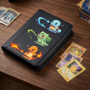 May include: Black zippered trading card binder featuring three Pokémon characters: Charmander, Bulbasaur, and Squirtle. Several Pokémon trading cards are visible on a wooden surface, including Charizard and Pikachu.