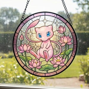 Może przedstawiać: Okrągły witraż przedstawiający różową postać z kreskówki z niebieskimi oczami, otoczoną różowymi kwiatami lotosu i zielonymi liśćmi. Okno jest oprawione w czarną ramę i zawieszone na łańcuchu.