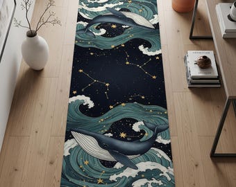 May include: A rectangular yoga mat featuring a dark blue night sky design with whales, waves, and constellations. The whales are dark blue with white bellies, and the waves are teal and white. Gold stars and constellations are scattered throughout.