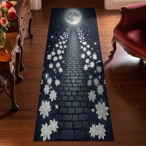 May include: A rectangular rug featuring a nighttime scene with a brick pathway leading to a full moon. White flowers line the path, and stars dot the dark blue sky. The rug is designed to be placed on a wooden floor.
