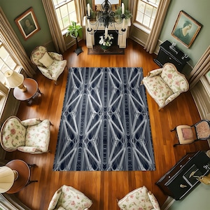 May include: A navy blue and white patterned area rug with a bridge design is the focal point of a room with hardwood floors. The room is furnished with floral patterned chairs, a fireplace, and artwork.