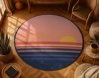 May include: A circular rug with a sunset design. The rug features a gradient of colours, including pink, yellow, orange, and blue. The design includes horizontal stripes and a yellow sun. The rug is placed on a wooden floor.