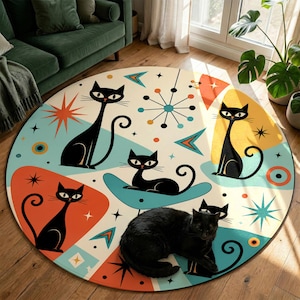 Op de afbeelding: Een rond vloerkleed met een modern design uit het midden van de eeuw met illustraties van zwarte katten op een crèmekleurige achtergrond. Het vloerkleed heeft een retro kleurenpalet van blauwgroen, oranje en geel. Een echte zwarte kat ligt op het kleed.