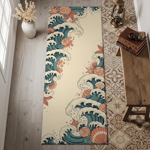May include: A rectangular beige rug with a stylized ocean wave design in teal and white, accented with coral-colored seashells and starfish. The rug is placed on a wooden floor, suggesting a coastal or nautical theme.