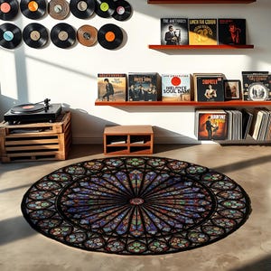 K&ouml;nnte beinhalten: Ein runder Teppich mit einem Buntglasfenster-Design in Blau-, Rot-, Gr&uuml;n- und Lilat&ouml;nen. Der Teppich liegt auf einem Betonboden. Ein Plattenspieler und Schallplatten sind im Hintergrund zu sehen.