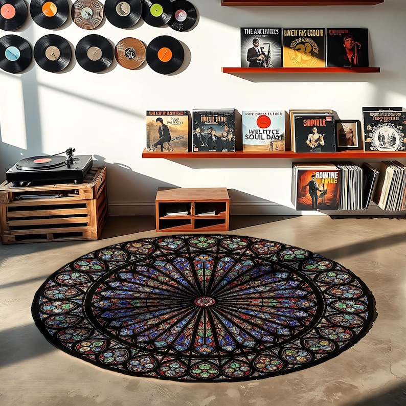 K&ouml;nnte beinhalten: Ein runder Teppich mit einem Buntglasfenster-Design in Blau-, Rot-, Gr&uuml;n- und Lilat&ouml;nen. Der Teppich liegt auf einem Betonboden. Ein Plattenspieler und Schallplatten sind im Hintergrund zu sehen.