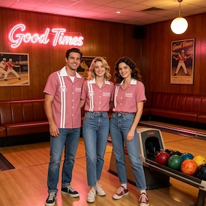 May include: Three individuals wearing matching dusty rose short-sleeved bowling shirts with white collars and vertical white stripes on the front. Each shirt features the word NAME embroidered in white on the chest and a bowling pin graphic.