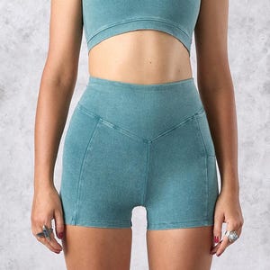 May include: A white ceramic mug with a black handle and the text "But First, Coffee" in a bold, black font. The mug is set against a blurred background, suggesting a cozy setting.