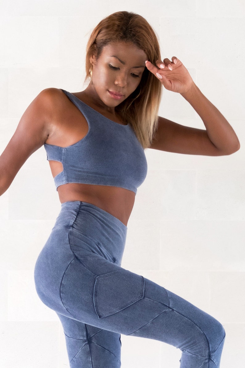Op de afbeelding: Een vrouw draagt een blauw crop top en bijpassende blauwe leggings met een geometrisch ontwerp. De leggings heeft een grote zak op de linkerdij.