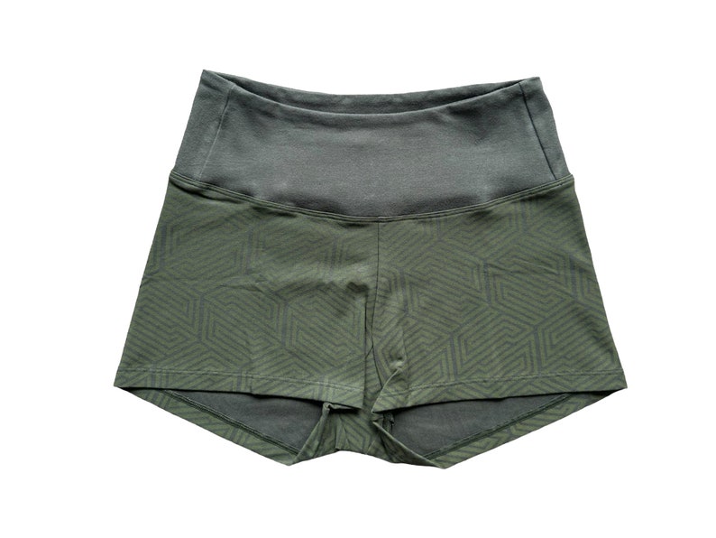 May include: Olive green athletic shorts with a geometric pattern on the lower portion and a solid gray waistband. The shorts are designed for comfort and movement, suitable for various fitness activities.