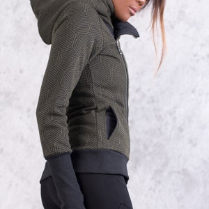 May include: A green and black patterned hooded jacket with a zipper closure. The jacket has a geometric pattern and a black zipper.