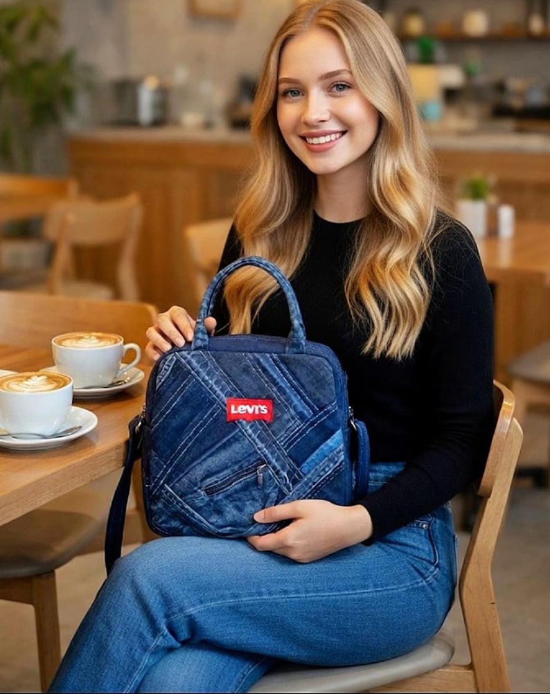 May include: A square-shaped denim handbag featuring a patchwork design of various blue denim fabric strips. The bag includes a top handle, a shoulder strap, and a prominent red rectangular Levi's brand label centered on the front exterior.