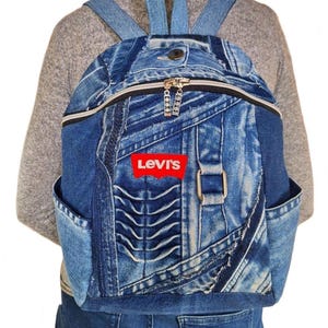 May include: Blue denim backpack with a zipper closure and side pockets. The backpack features the Levi's logo in red on the front. The straps and back panel are a lighter shade of blue.