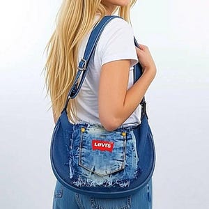 May include: A denim shoulder bag with a distressed pocket featuring the Levi's logo. The bag has a rounded shape, adjustable straps, and gold-colored hardware. The bag is made from blue denim.