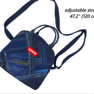 May include: A dark blue denim patchwork backpack featuring a red Levi's brand tag, two top handles, and an adjustable strap measuring 47.2 inches. The bag includes a front pocket with a gold-toned zipper closure and various shades of blue denim fabric.