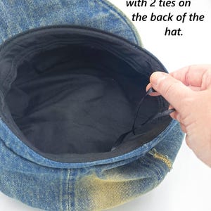 May include: Denim newsboy hat with a black interior lining. The hat's size is adjustable with ties at the back. The hat size is 22"-23.2" (56-58 cm).