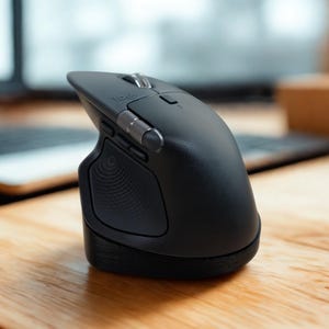 May include: A black ergonomic computer mouse with silver accents. The mouse has a curved design with a thumb rest and multiple buttons. It sits on a wooden surface, with a keyboard and monitor in the background.