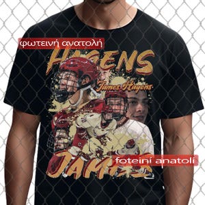 Può includere: T-shirt nera con un design a tema hockey. La maglietta presenta un collage di giocatori di hockey, il nome "HAGENS" in oro e il nome "James Hagens". È presente anche il testo greco "φωτεινή ανατολή" e "foteiní anatolí".