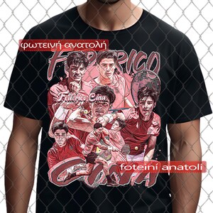 以下が含まれることがあります： 黒いTシャツ。赤と白のテニス選手のコラージュ。デザインには「Federico Cina」の名前とギリシャ語のテキストが含まれています。テニスラケットとボールがスポーツをテーマにしたグラフィックに表示されています。