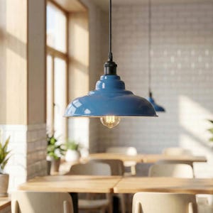 May include: A blue metal pendant light fitting with a wide, dome-shaped shade and a black flex. The lamp features a glossy finish, a black socket at the top, and a single exposed Edison-style light bulb hanging from the centre of the shade.