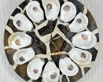 May include: A round wall clock featuring a dark brown and cream giraffe-print background. Twelve white oyster shells serve as hour markers around the perimeter. A circular ring of amber and brown glass beads surrounds the central black clock hands.