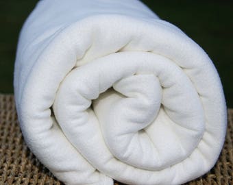 May include: A white fleece blanket rolled up, showing the soft texture of the fabric.
