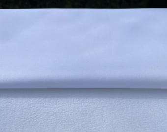 May include: A white satin fabric with a smooth, silky texture. The fabric is folded in half, revealing the underside.