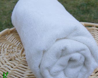 May include: A white rolled up towel, made of soft, fluffy terry cloth, is sitting on a woven wicker basket.